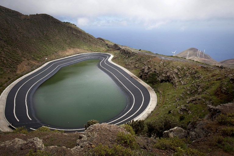 La STEP de l’ile d’El Hierro, avec son réservoir supérieur qui communique avec la mer via une station de pompage et de turbinage. À l’arrière-plan, les éoliennes qui alimentent les pompes.