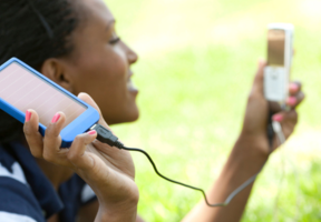 jeune femme rechargeant son portable grâce à sa batterie solaire