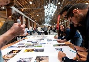 Jeunes gens collant des images sur une bache blanche pour constituer une fresque du climat