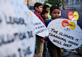 Un jeune Indien qui tient une pancarte en forme d’appel : « le climat change, quand changerons-nous ? »