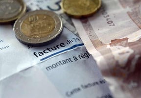 Photo of euro notes and coins on top of an electricity bill