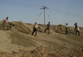 Des ouvriers chinois manipulent les résidus d'usines de traitement de terres rares, près de la ville de Baotou, en Mongolie intérieure (Chine).  