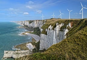 Image of wind turbines on the crest of a cliff, a sign of the rise of renewable energies in Europe.