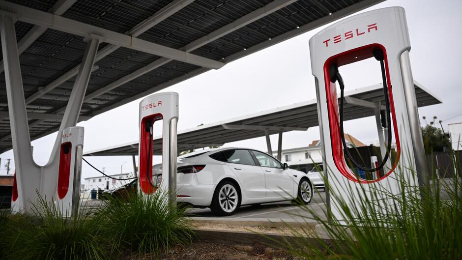 Des véhicules électriques Tesla qui se rechargent sur des bornes de recharge situées sous des panneaux solaires dans une station Tesla Supercharger à Santa Monica.