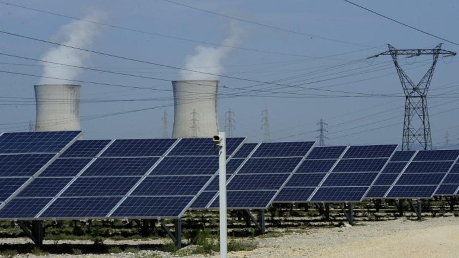 Photo of photovoltaic panels in front of the cooling towers of the Tricastin nuclear power plant in Provence.