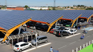 Une photo d'un supermarché du sud de la France dont le parking est recouvert d'ombrières photovoltaïques.