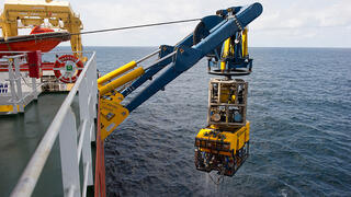 Deep offshore production requires the use of sophisticated robotic equipment. Here we see a remotely operated vehicle (ROV) being launched.