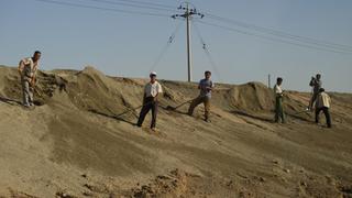 Des ouvriers chinois manipulent les résidus d'usines de traitement de terres rares, près de la ville de Baotou, en Mongolie intérieure (Chine).  