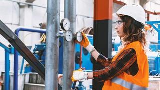 Industrial worker regulating the pressure of a compressed air pressure valve