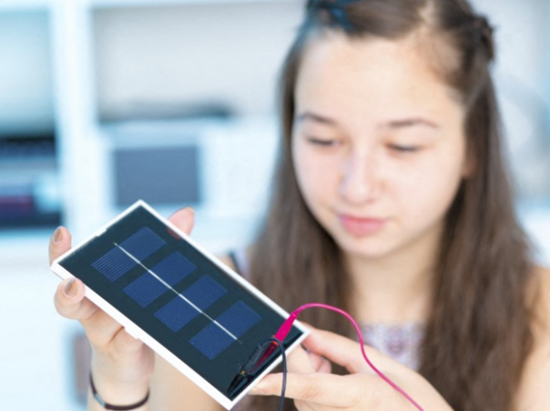 A young girl connecting cables to a small photovoltaic panel