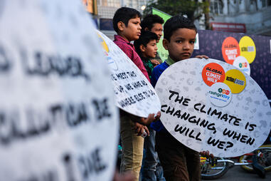 Un jeune Indien qui tient une pancarte en forme d’appel : « le climat change, quand changerons-nous ? »