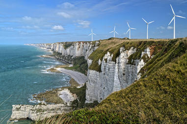 Image of wind turbines on the crest of a cliff, a sign of the rise of renewable energies in Europe.